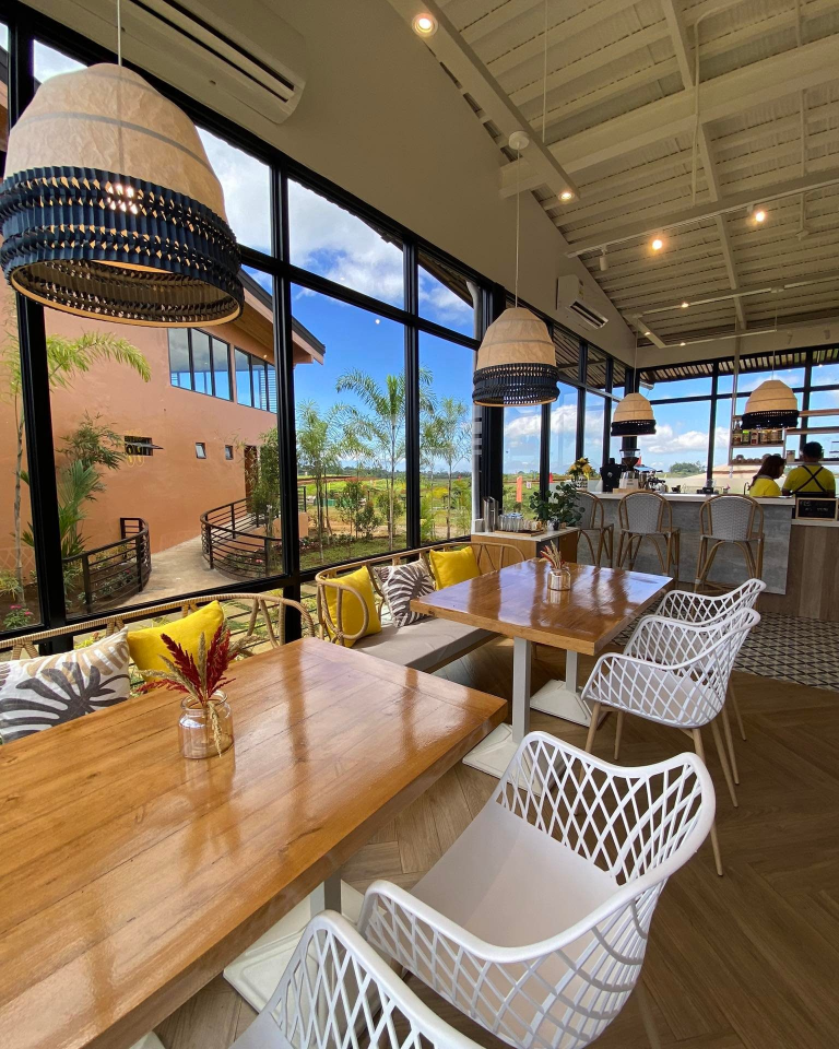 Skye 88 Cafe's interior showcases a bright and airy space with multiple seating options, including a bar area, all with expansive views. The design is modern, stylish, and emphasizes natural light.