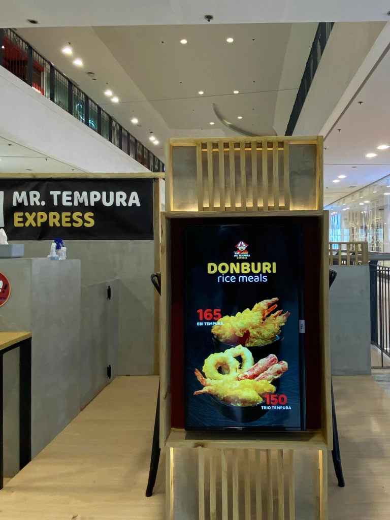 Mr. Tempura Express features a modern and efficient food stall design within a shopping mall. This image showcases the stall's interior, highlighting the menu board and minimalist aesthetic.