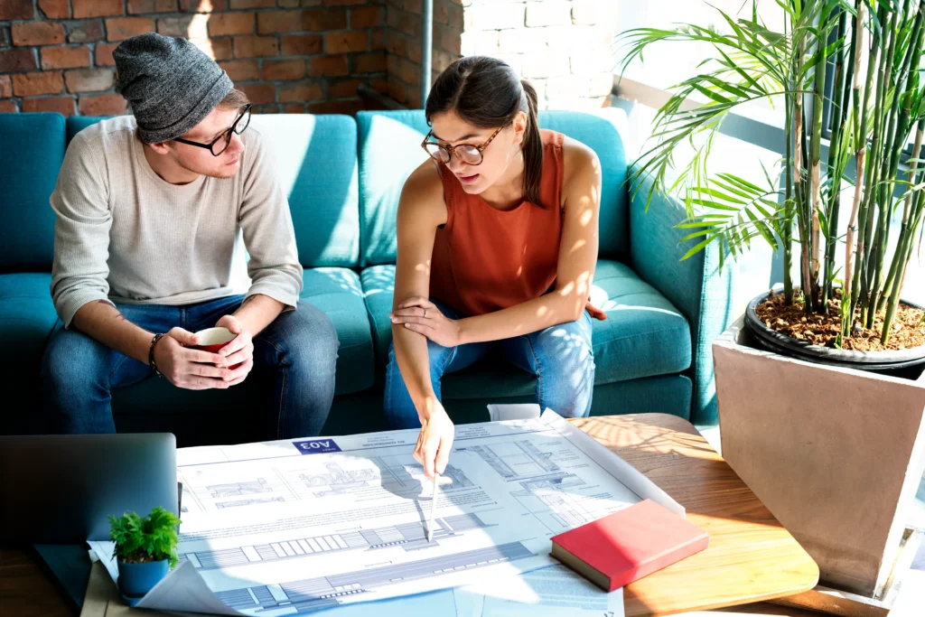designer and clients are collaborating on a space plan, reviewing layout options together. This image emphasizes the collaborative and personalized approach to space planning.