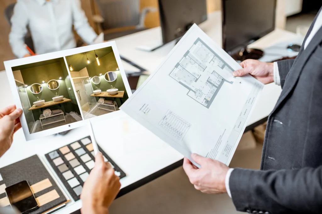 A client and designer review design plans and material samples together, showcasing the collaborative process of planning a bathroom renovation.