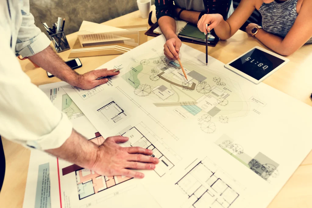Designers collaboratively reviewing detailed floor plans, emphasizing the importance of careful planning for optimal space function and flow.